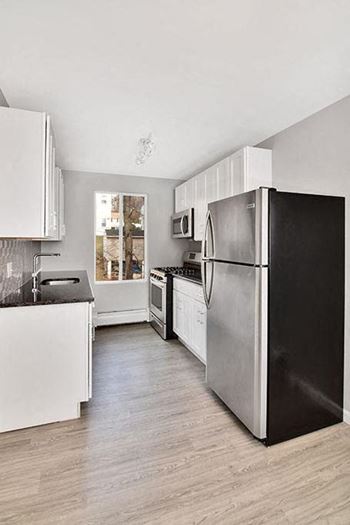 a kitchen with a black refrigerator and white cabinets at Springwood Gardens, New Britain, 06053